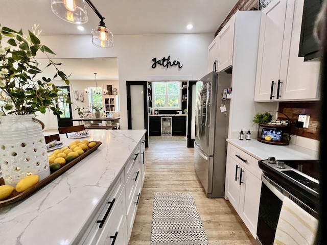 kitchen featuring white cabinets, light wood-style flooring, wine cooler, freestanding refrigerator, and black electric range