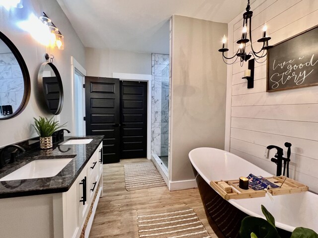 full bathroom with wood finished floors, a soaking tub, a sink, and an inviting chandelier