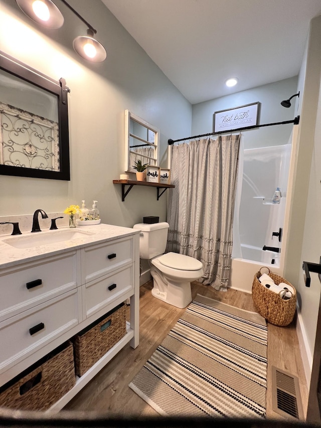 bathroom featuring toilet, wood finished floors, vanity, visible vents, and shower / tub combo with curtain