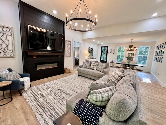 living room with a large fireplace, baseboards, wood finished floors, a chandelier, and recessed lighting