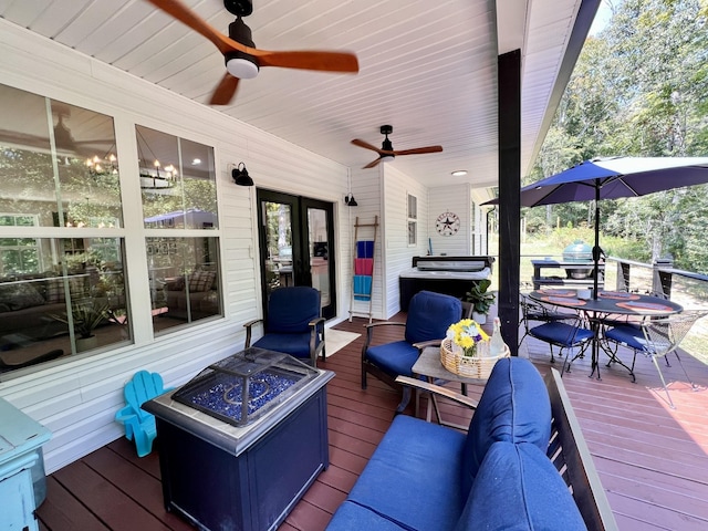 deck featuring ceiling fan, a fire pit, french doors, and outdoor dining space