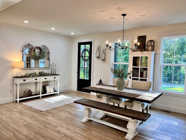 dining space with an inviting chandelier, wood finished floors, and a healthy amount of sunlight