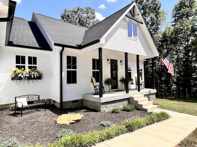 view of front of home featuring a shingled roof, covered porch, and crawl space