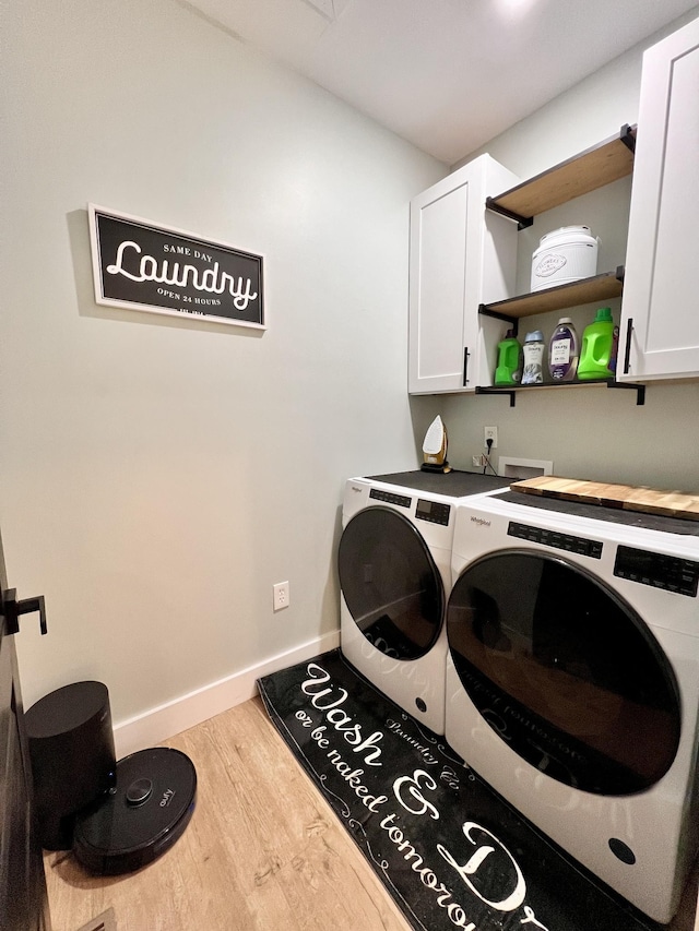 washroom featuring washer and dryer, cabinet space, baseboards, and wood finished floors