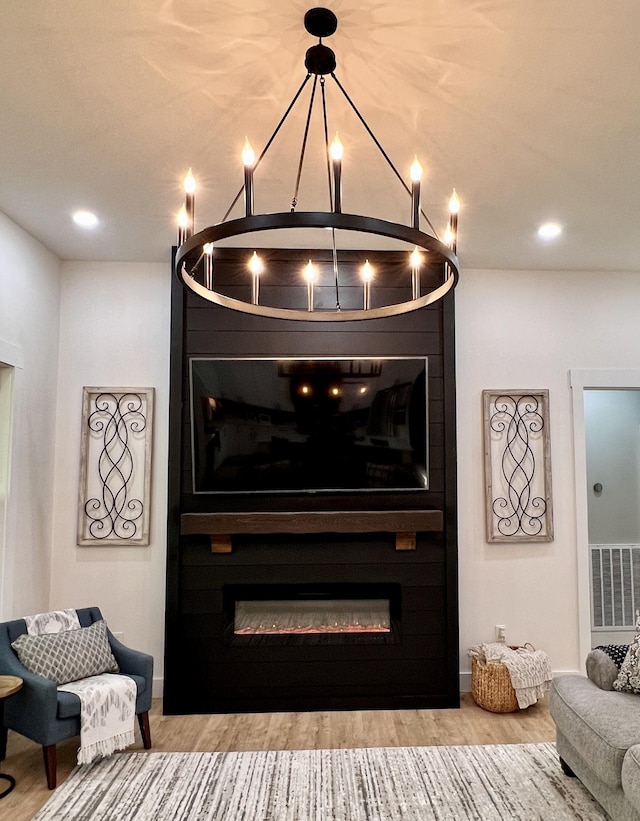 interior details featuring visible vents, an inviting chandelier, a large fireplace, wood finished floors, and baseboards