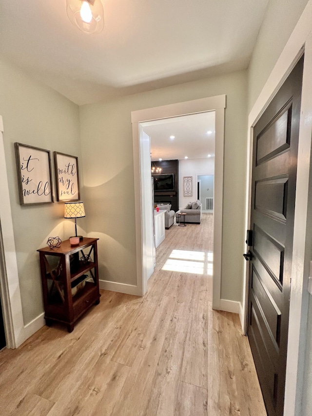 hallway featuring light wood-style floors, visible vents, and baseboards