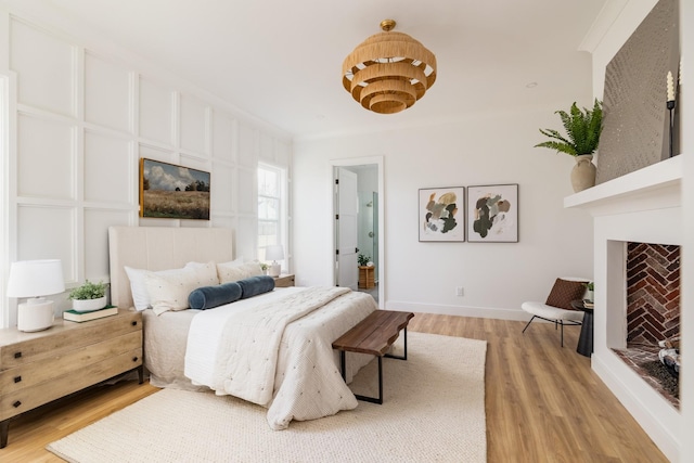 bedroom featuring baseboards, a fireplace, and light wood finished floors