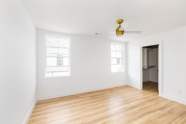 unfurnished room with visible vents, light wood finished floors, a ceiling fan, and baseboards