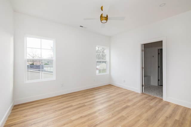 empty room featuring visible vents, light wood-type flooring, a ceiling fan, and baseboards