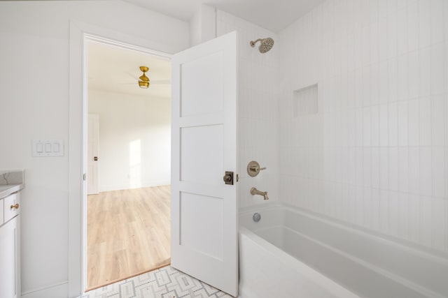 bathroom with washtub / shower combination, wood finished floors, and vanity