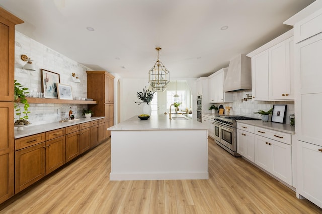 kitchen with light countertops, appliances with stainless steel finishes, light wood-type flooring, and custom exhaust hood