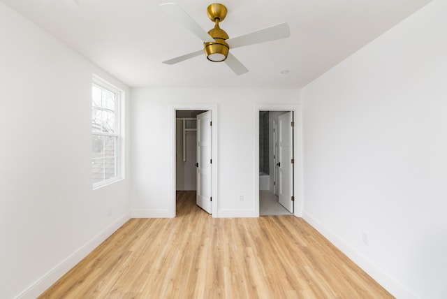 unfurnished bedroom with baseboards, ceiling fan, a walk in closet, light wood-type flooring, and a closet