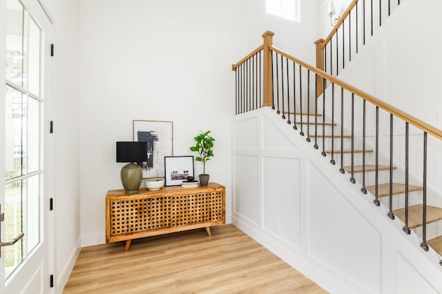 stairway featuring wood finished floors, a towering ceiling, and baseboards