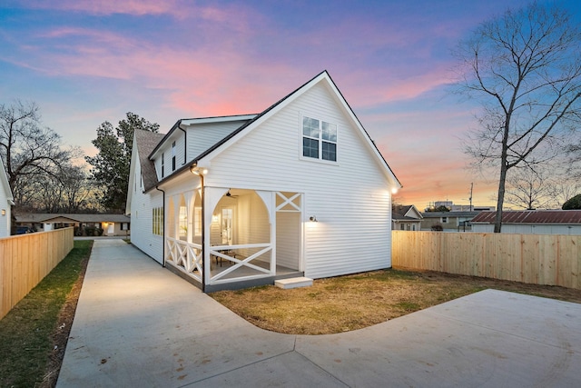 back of property with fence, concrete driveway, and a patio