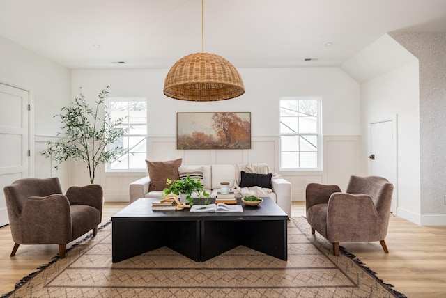 living room featuring light wood-type flooring, visible vents, and wainscoting