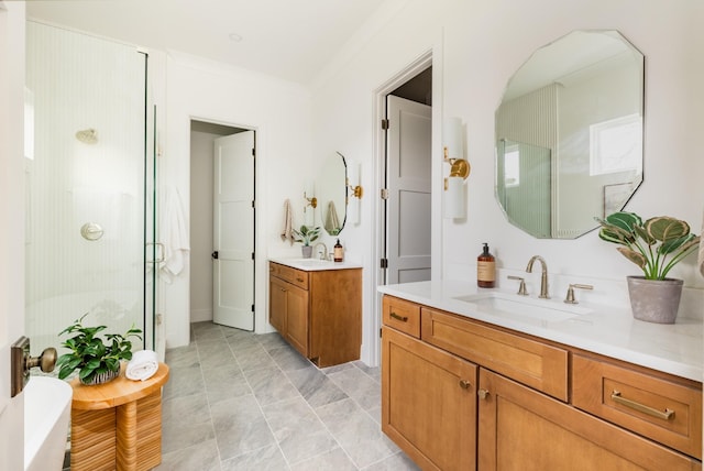 full bathroom with a shower stall, crown molding, two vanities, and a sink