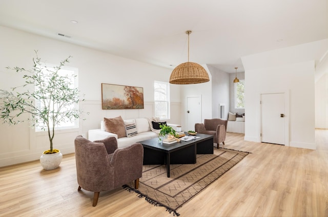 living room with light wood-type flooring, baseboards, and visible vents