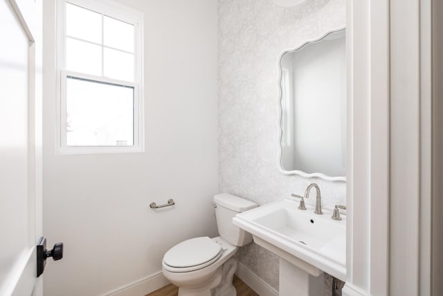 bathroom with toilet, baseboards, a sink, and wood finished floors