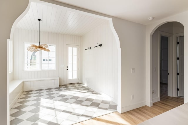 foyer with light floors, baseboards, and arched walkways