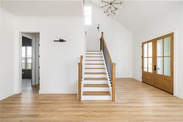 entryway featuring french doors, baseboards, light wood finished floors, and stairs