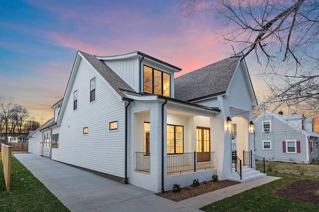 view of front of property featuring a shingled roof, board and batten siding, and brick siding