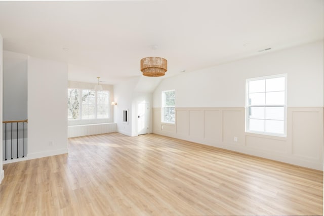 empty room featuring a wainscoted wall, visible vents, and light wood finished floors