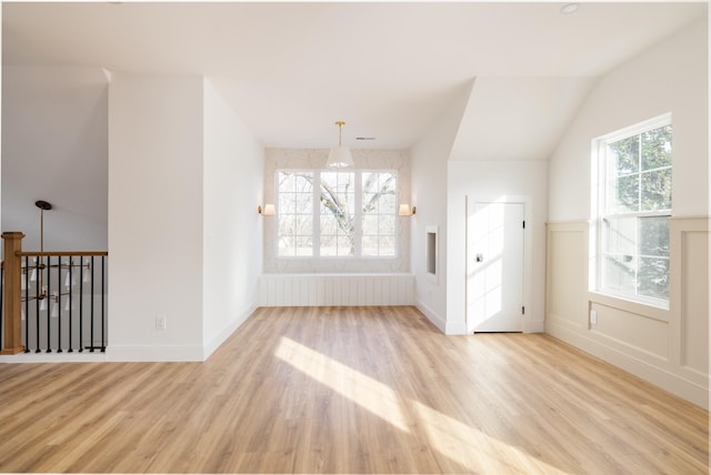 unfurnished room featuring lofted ceiling, baseboards, an inviting chandelier, and wood finished floors