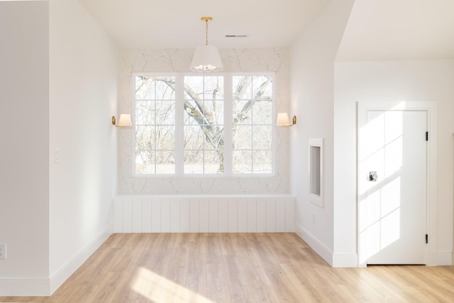 unfurnished dining area with baseboards, visible vents, radiator heating unit, and wood finished floors