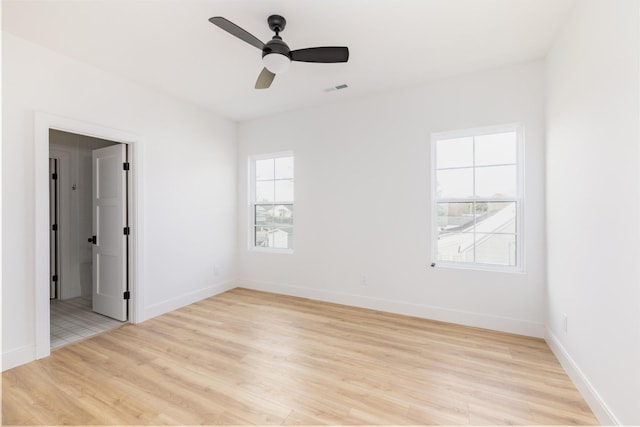 spare room with a wealth of natural light, visible vents, light wood-style flooring, and baseboards