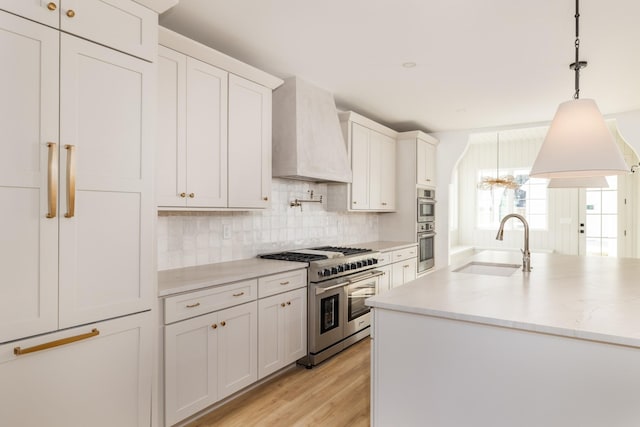 kitchen with custom exhaust hood, stainless steel appliances, backsplash, light wood-style floors, and a sink