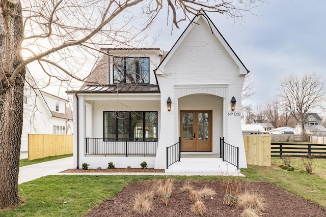 view of front of home with french doors, a porch, fence, and brick siding