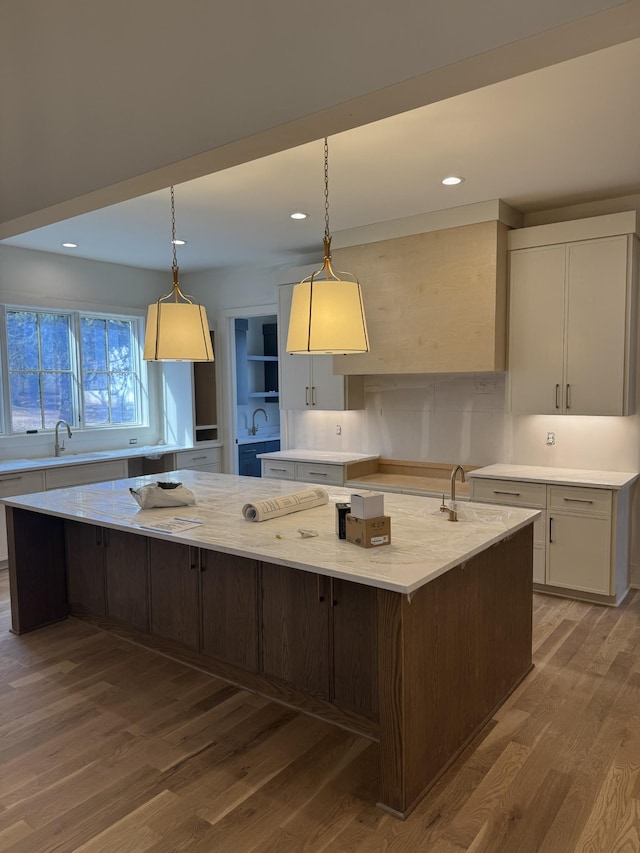 kitchen with a spacious island, white cabinets, and wood finished floors