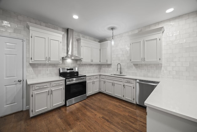 kitchen with wall chimney exhaust hood, appliances with stainless steel finishes, dark wood-style flooring, light countertops, and a sink