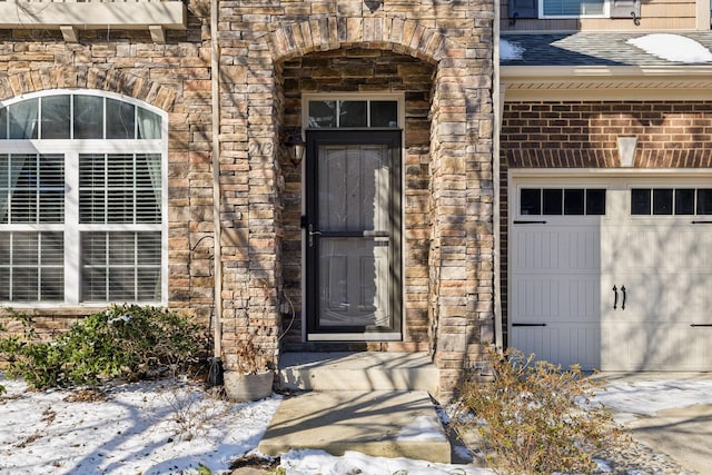 doorway to property with a shingled roof, stone siding, and brick siding