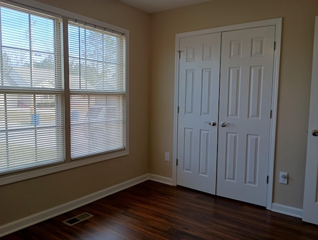 unfurnished bedroom featuring dark wood-type flooring, visible vents, and baseboards