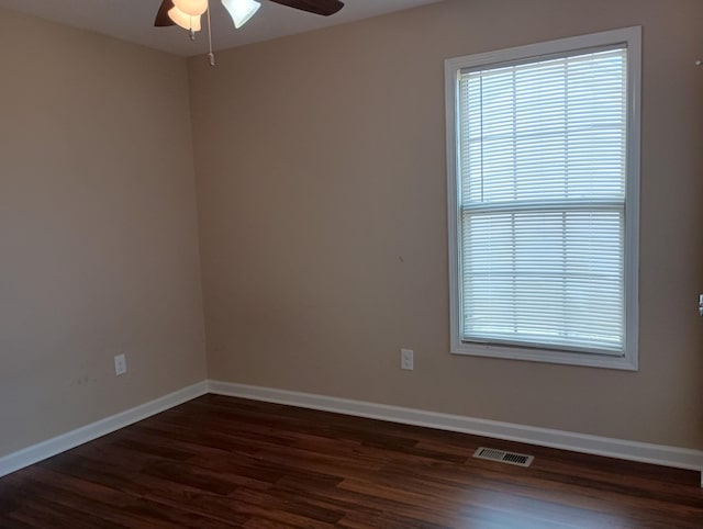 spare room with dark wood-style floors, baseboards, visible vents, and a ceiling fan