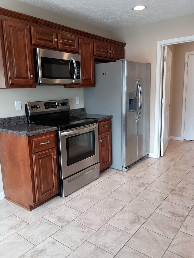 kitchen featuring a textured ceiling, appliances with stainless steel finishes, and light tile patterned floors