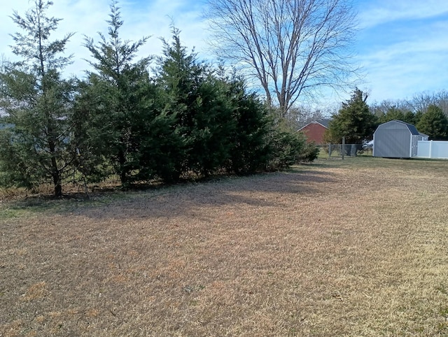 view of yard featuring a shed, an outdoor structure, and fence