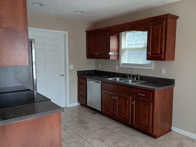 kitchen with dark countertops, appliances with stainless steel finishes, a sink, a textured ceiling, and baseboards