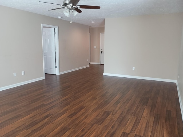 spare room with a textured ceiling, ceiling fan, dark wood-type flooring, and baseboards