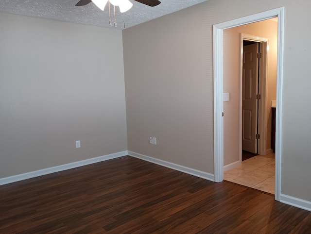 spare room with a textured ceiling, wood finished floors, a ceiling fan, and baseboards