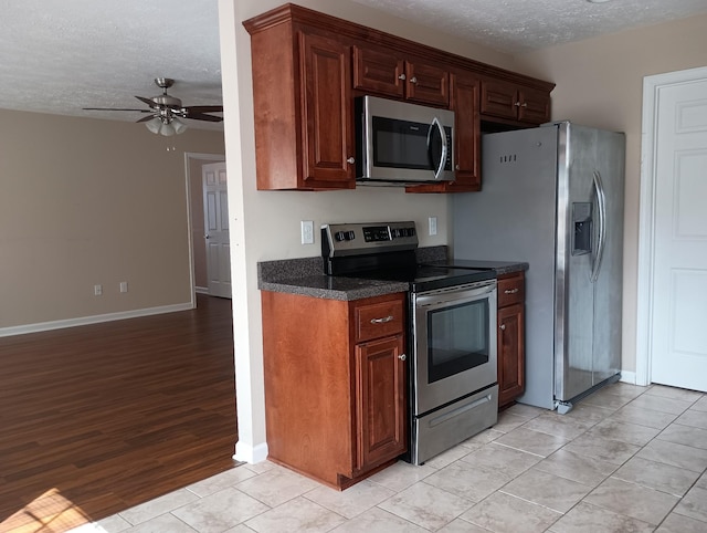 kitchen with a ceiling fan, baseboards, appliances with stainless steel finishes, and a textured ceiling