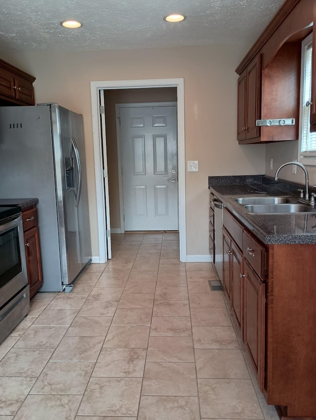 kitchen with light tile patterned floors, a textured ceiling, stainless steel appliances, and a sink