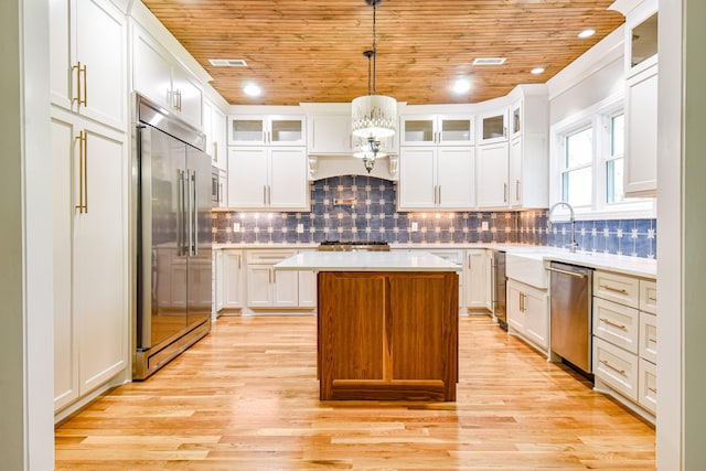 kitchen featuring built in appliances, light countertops, a kitchen island, and wood ceiling