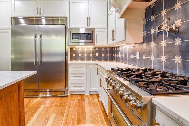 3635 Old Williamsport Rd, Williamsport, TN 38487 - kitchen featuring backsplash, light wood-style floors, white cabinets, light stone countertops, and built in appliances