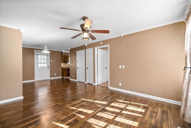 spare room featuring dark wood-style floors, ceiling fan, baseboards, and ornamental molding