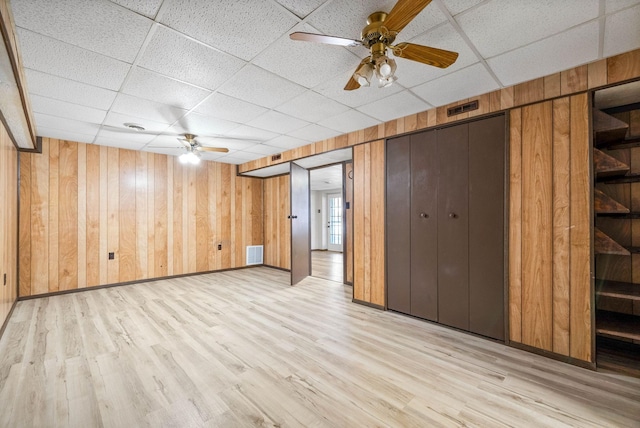 finished below grade area featuring light wood-type flooring, visible vents, and wooden walls