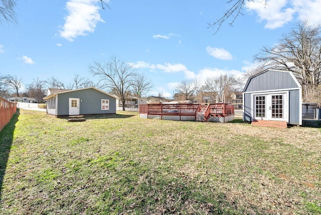 view of yard with fence, a deck, and an outdoor structure