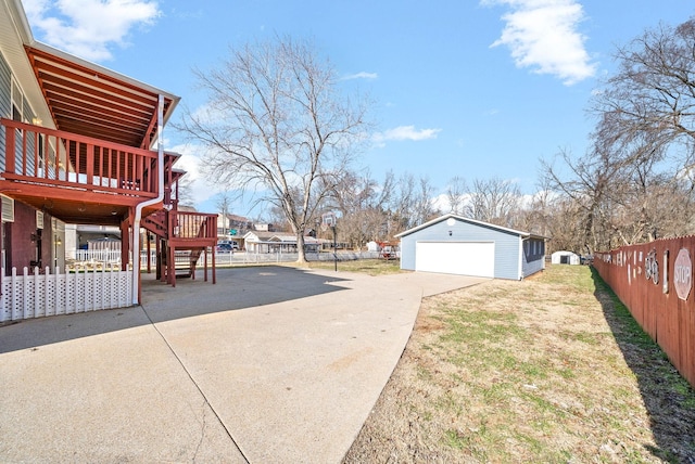 view of yard with a detached garage, an outbuilding, stairs, fence, and a deck