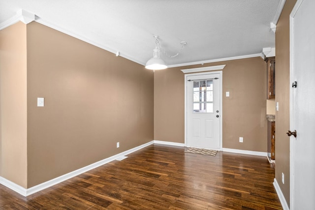 entrance foyer with dark wood-type flooring, ornamental molding, and baseboards